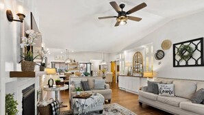 A spacious living room with a fireplace, a ceiling fan, and a large rug. - 123 Washington · Charming Modern Farmhouse Style Home in Downtown Monument (Monument)
