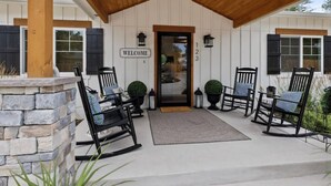 A covered porch with a 'WELCOME' sign, numbered doors, and outdoor seating. - 123 Washington · Charming Modern Farmhouse Style Home in Downtown Monument (Monument)