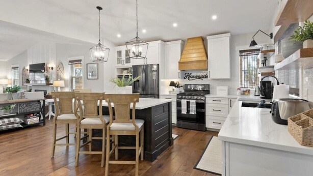 A modern kitchen with a central island, wooden chairs, and a dining table. - 123 Washington · Charming Modern Farmhouse Style Home in Downtown Monument (Monument)