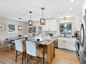 A modern kitchen with white cabinets, a central island, pendant lighting, and a stainless steel refrigerator. - 52 Front St · HOT TUB! Amazing Mountain views!  Newly Remodeled (Monument)