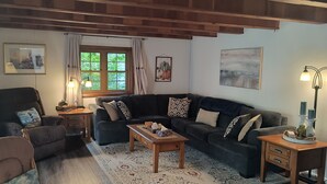 En hyggelig stue med en mørk sofa, et træbord og en lampe på et sengebord.