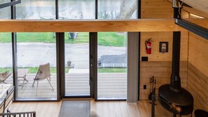 En modern stuga med ett stort glasfönster, en öppen spis och en uteplats.