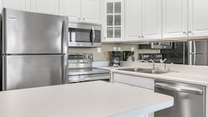 A modern kitchen with stainless steel appliances, white cabinetry, and a central island.