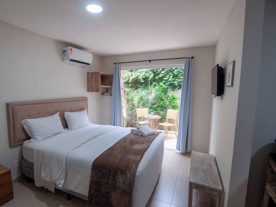 Una camera da letto con un letto, un comodino, un armadio e una finestra vista sul verde.