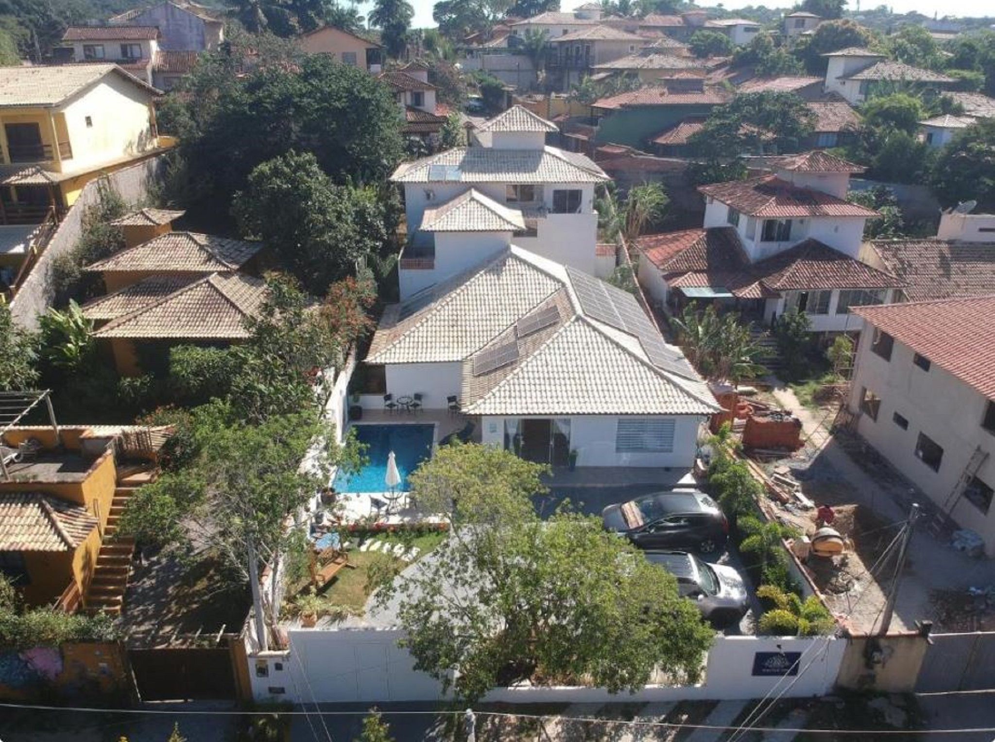 A residential area with multiple houses, a swimming pool, and a parked car.