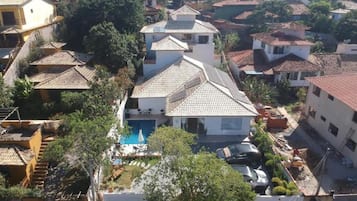 A residential area with multiple houses, a swimming pool, and a parked car.