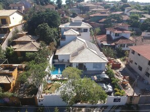 A residential area with multiple houses, a swimming pool, and a parked car. - Pousada Maktub (Búzios)