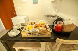 A breakfast buffet with various food items and a coffee maker on a kitchen counter. - Pousada Maktub (Búzios)