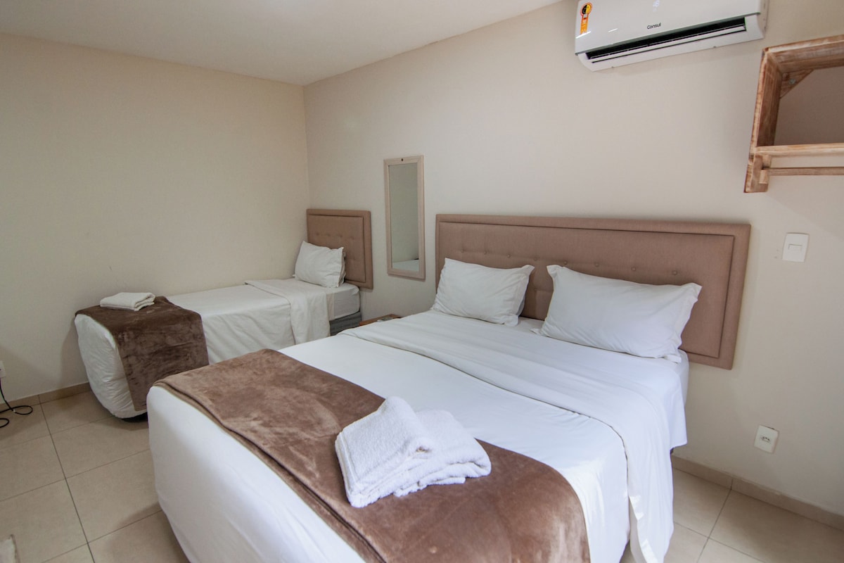 Una habitación de hotel con dos camas, un espejo grande y un equipo de aire acondicionado.