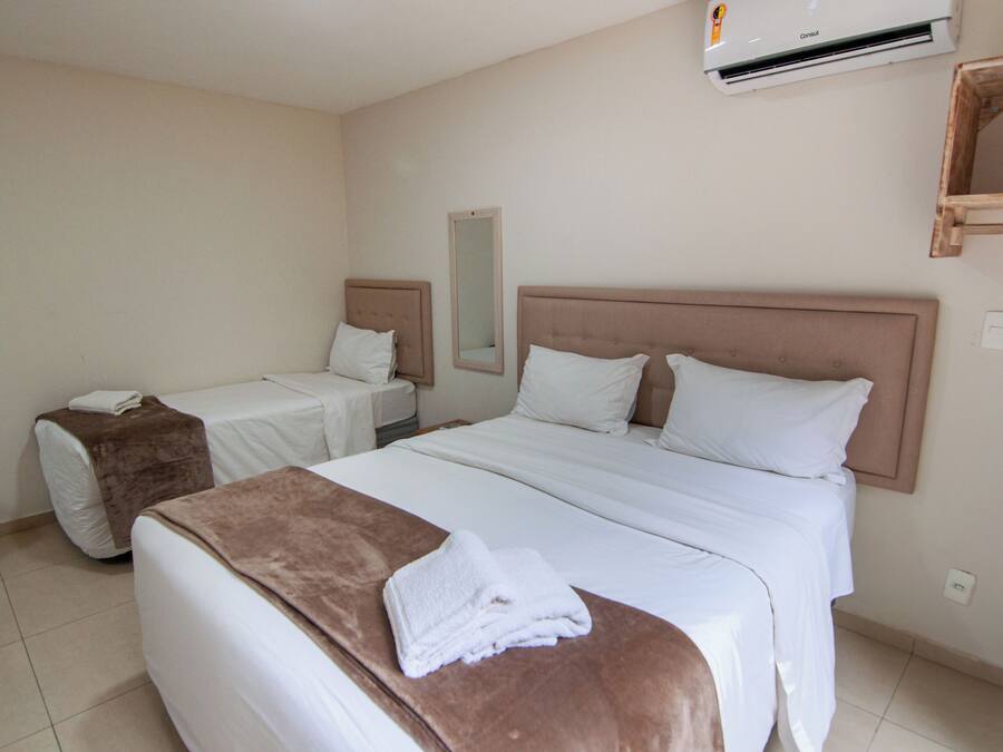 Una habitación de hotel con dos camas, un espejo grande y un equipo de aire acondicionado.