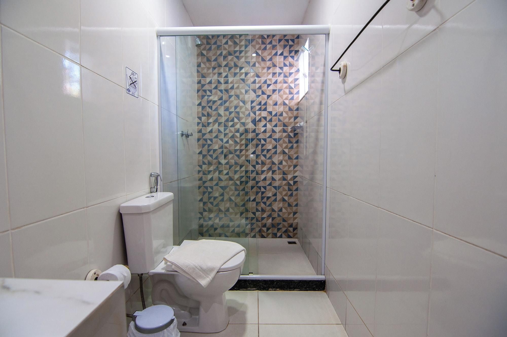 A small bathroom with a toilet, a sink, and a shower stall with a geometric tile pattern.