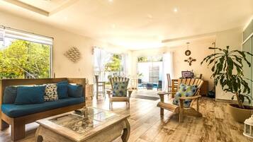 Un salón amplio con una mesa de centro de madera, un sofá con cojines azules y dos sillones.