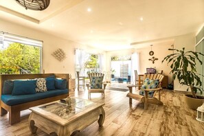 Un salón amplio con una mesa de centro de madera, un sofá con cojines azules y dos sillones.