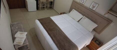 A bedroom with a bed, bedside tables, a desk, and chairs.