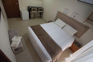 A bedroom with a bed, bedside tables, a desk, and chairs.
