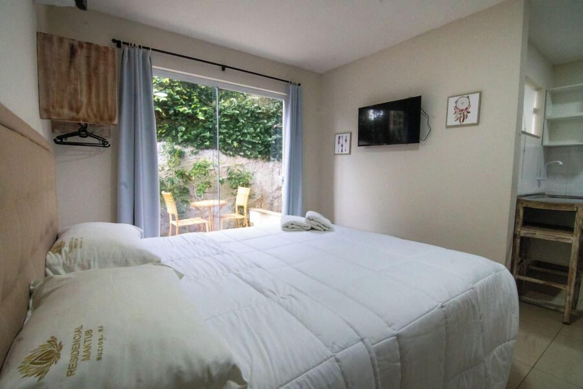 A bedroom with a bed, a TV, and a small table.