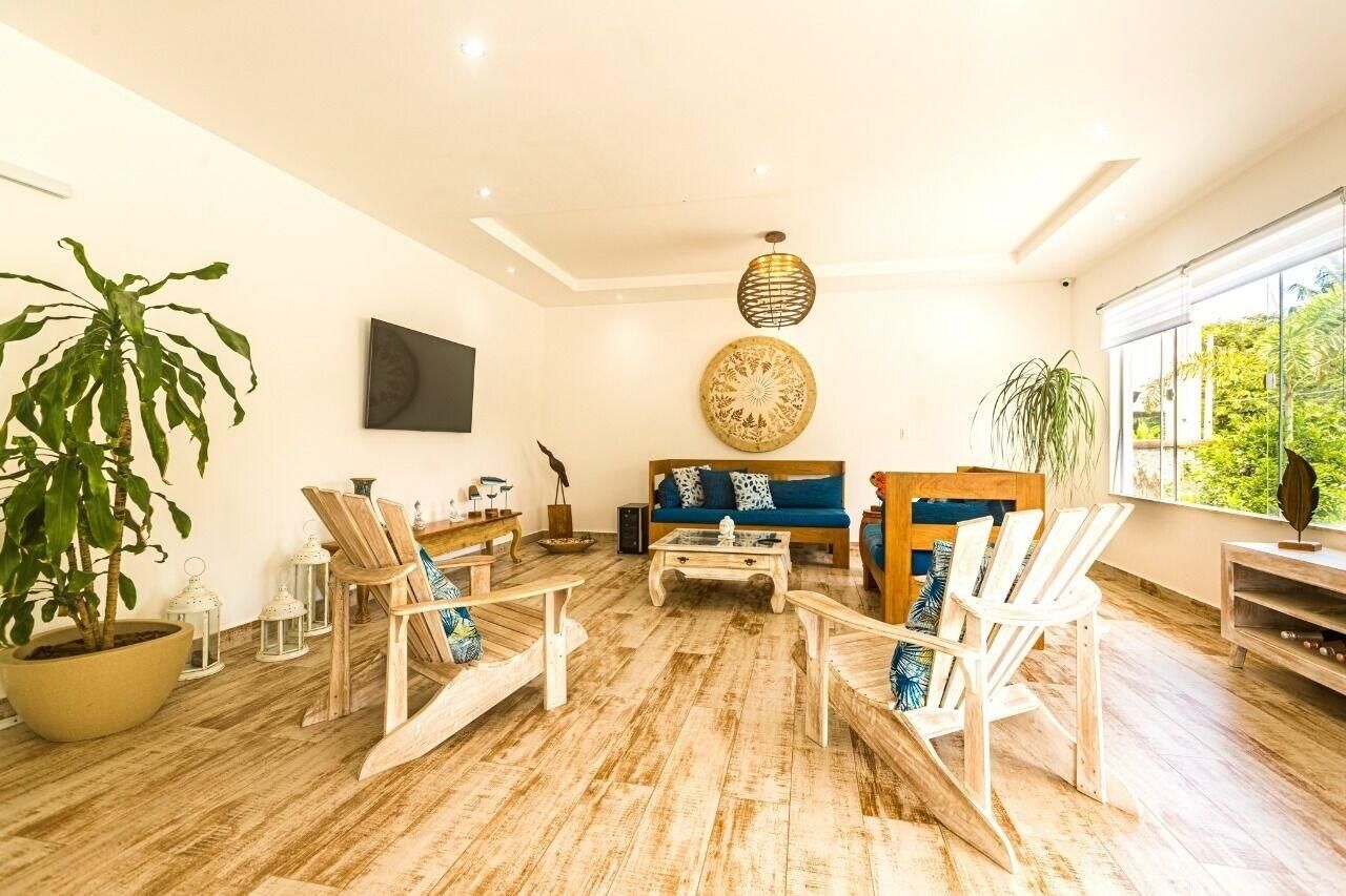 Ein geräumiges Wohnzimmer mit einem blauen Sofa, Holzstühlen, einem Couchtisch und einer großen Küstpflanze.