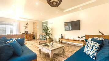 Un salon spacieux avec un grand canapé, une table basse et un téléviseur fixé au mur.