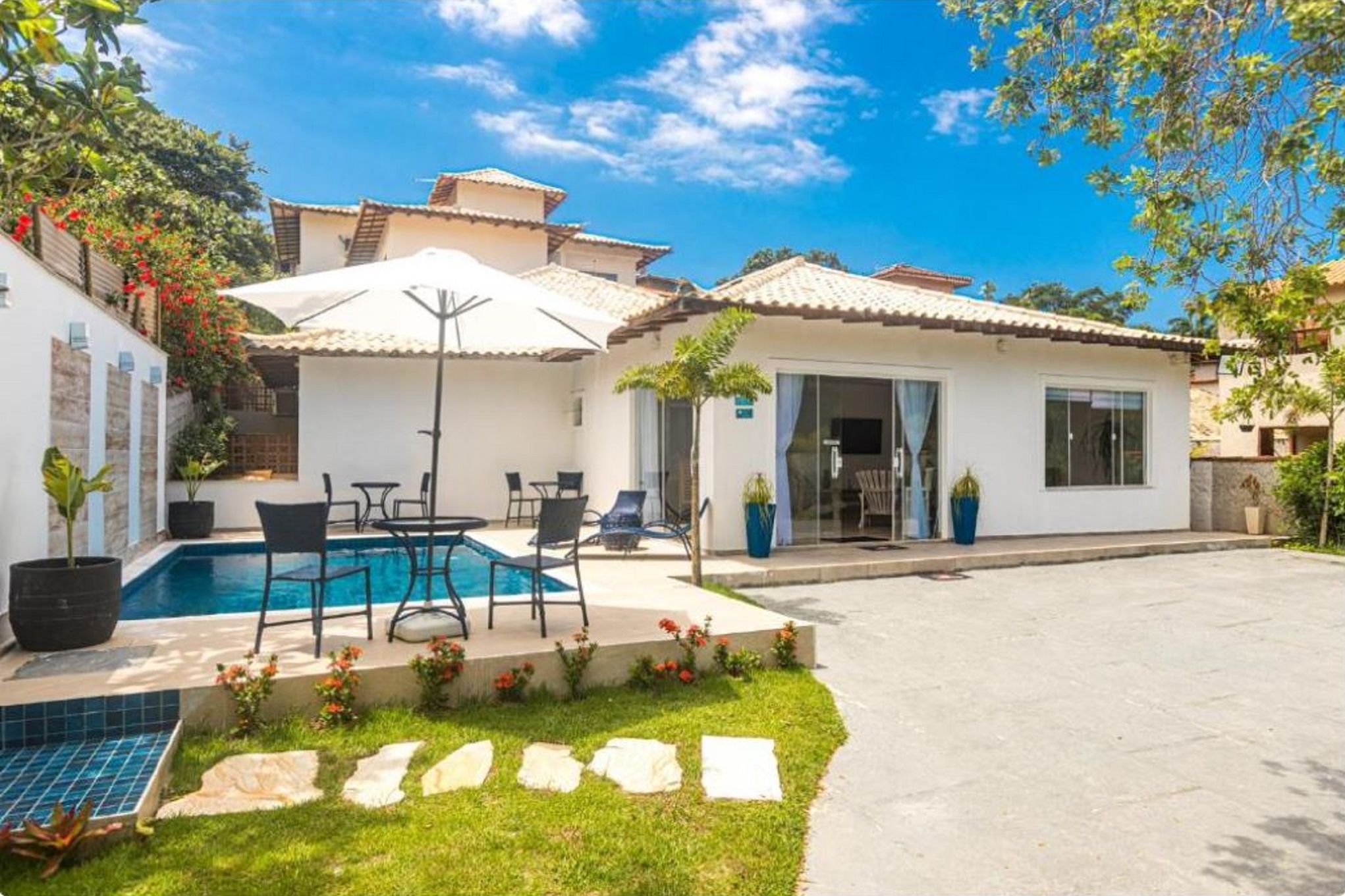 Una propiedad residencial con piscina, mobiliario exterior y terraza cubierta.