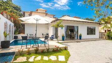 Una propiedad residencial con piscina, mobiliario exterior y terraza cubierta.