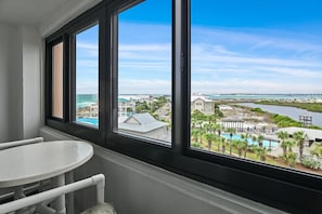 A room with a large window overlooking a resort area, including a pool and buildings.