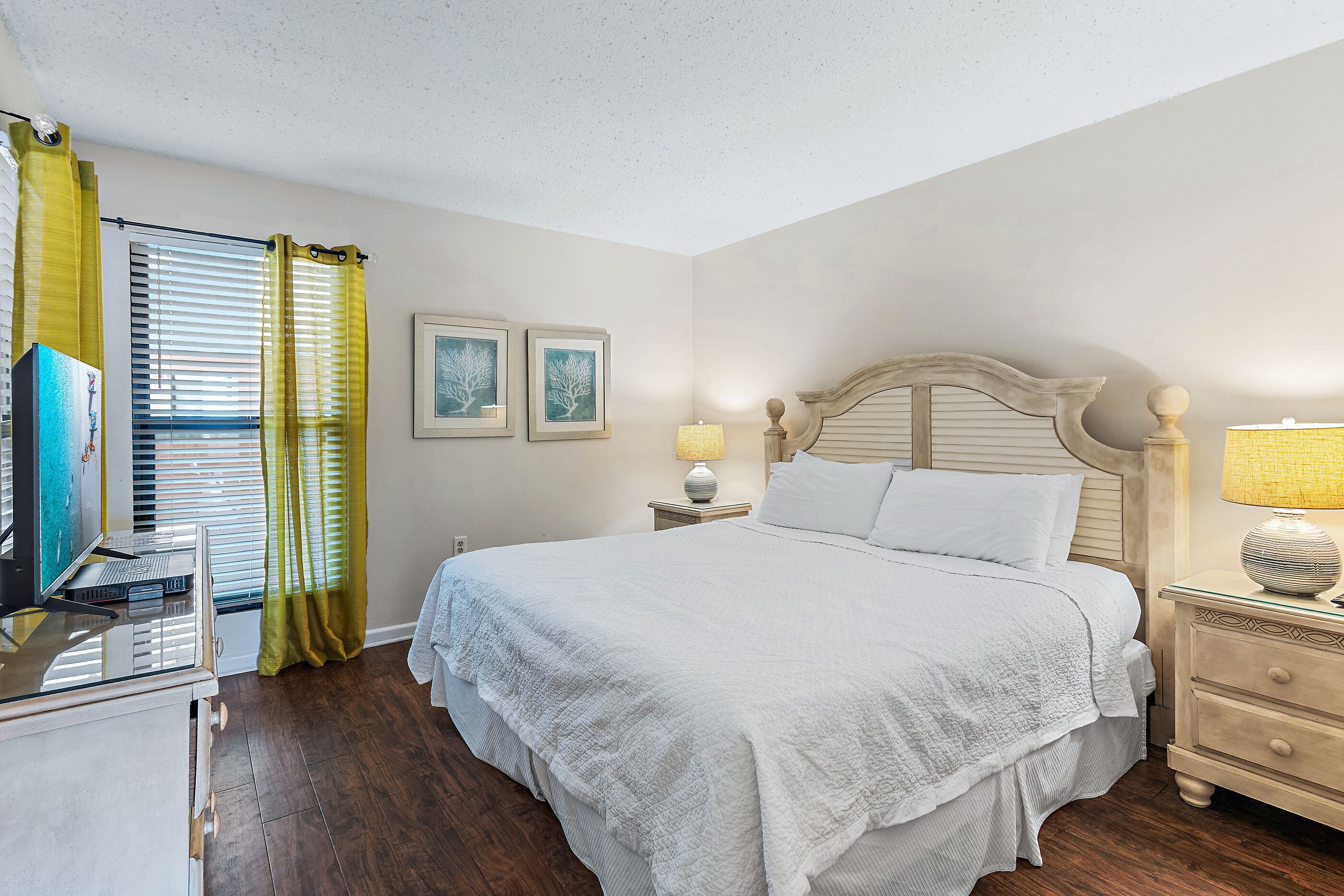 A bedroom with a bed, bedside tables, a desk, and a television.