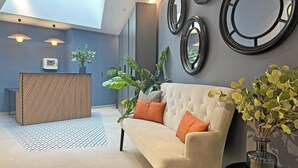 A modern lobby with a reception desk, a cushioned seating area, and decorative mirrors. - Apartamentos Soho Boutique Palillero (Cádiz)