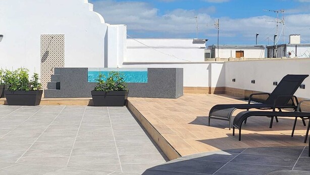 A rooftop terrace with a swimming pool, lounge chairs, and potted plants. - Apartamentos Soho Boutique Palillero (Cádiz)