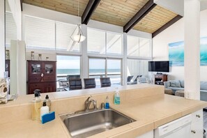 A spacious kitchen with a large island, a built-in sink, and a view of the ocean through large windows. - Sand Dollar Beachfront Home, Direct Beach Access! (La Selva Beach)