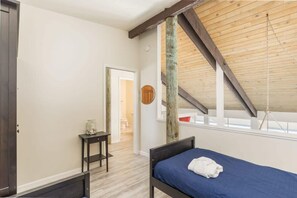 A bedroom with a sloped ceiling, a bed with a blue mattress, a small bedside table, and a nightstand. - Sand Dollar Beachfront Home, Direct Beach Access! (La Selva Beach)