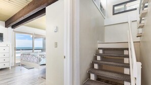 Un escalier dont les marches sont recouvertes de moquette, menant à un balcon d’où l’on peut admirer la mer.