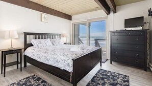 A bedroom with a bed, a dresser, a television, and a view of the outdoors. - Sand Dollar Beachfront Home, Direct Beach Access! (La Selva Beach)
