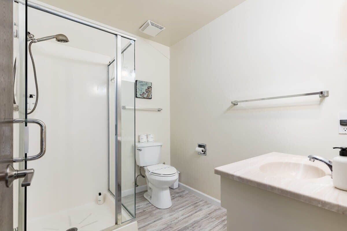 Une salle de bain avec une douche à parois de verre, des toilettes, un lavabo et un porte-serviettes.