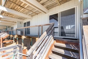 A construction site with wooden steps leading to a covered area, metal fencing, and a large sliding glass door. - Sand Dollar Beachfront Home, Direct Beach Access! (La Selva Beach)