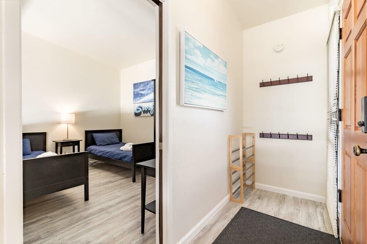 A hotel room with a bed, a desk, a chair, a lamp, and a painting on the wall.