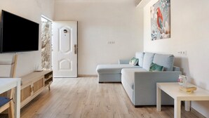 Un soggiorno moderno con una televisione a schermo piatto, un divano blu chiaro, un tavolino con un libro e un quadro raffigurante un pappagallo sulla parete.
