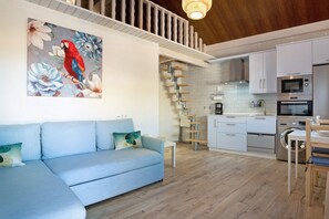 A modern kitchen with white cabinets, stainless steel appliances, and a wooden staircase.