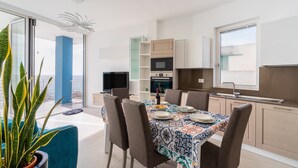 Une cuisine moderne avec un coin repas, une grande plante en pot et une vue sur la mer.
