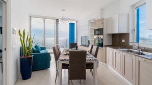 Une cuisine moderne avec un coin repas, de grandes fenêtres et une vue sur la mer.