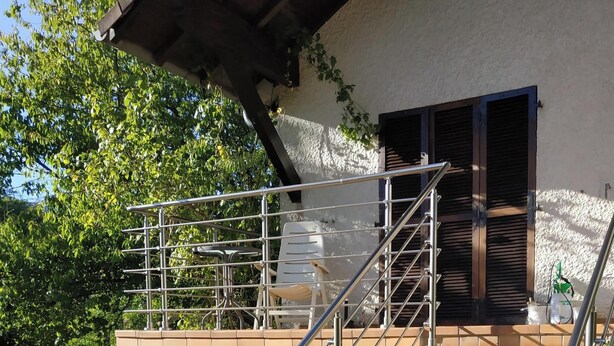 A staircase leading to a covered outdoor area with a metal railing, a white plastic chair, and a gas pump. - "Diff" Chalet 150m from the Lake, Private Garden and Wi-Fi (Puttelange-aux-Lacs)