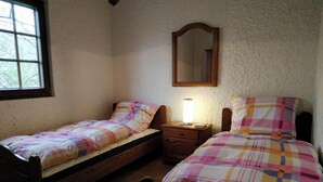 A small bedroom with two single beds, a nightstand with a lamp, a mirror, and a window. - "Diff" Chalet 150m from the Lake, Private Garden and Wi-Fi (Puttelange-aux-Lacs)