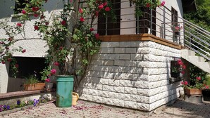 A house with a stone facade, a wooden balcony, and a rose bush climbing the wall. - "Diff" Chalet 150m from the Lake, Private Garden and Wi-Fi (Puttelange-aux-Lacs)