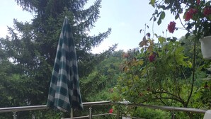 A patio with a round table and two chairs, a metal railing, and a view of greenery. - "Diff" Chalet 150m from the Lake, Private Garden and Wi-Fi (Puttelange-aux-Lacs)