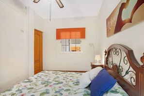 Quarto com cama, janela com persianas, porta e uma obra de arte na parede.