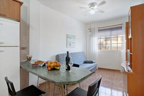 A kitchen with a dining table, chairs, a sofa, and a ceiling fan.