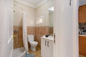 Une salle de bain équipée d’une douche, de toilettes et d’un lavabo avec un miroir au-dessus.