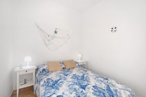 Une chambre à coucher comprenant un lit, deux tables de chevet, une commode, un hamac fixé au mur et un élément décoratif mural.