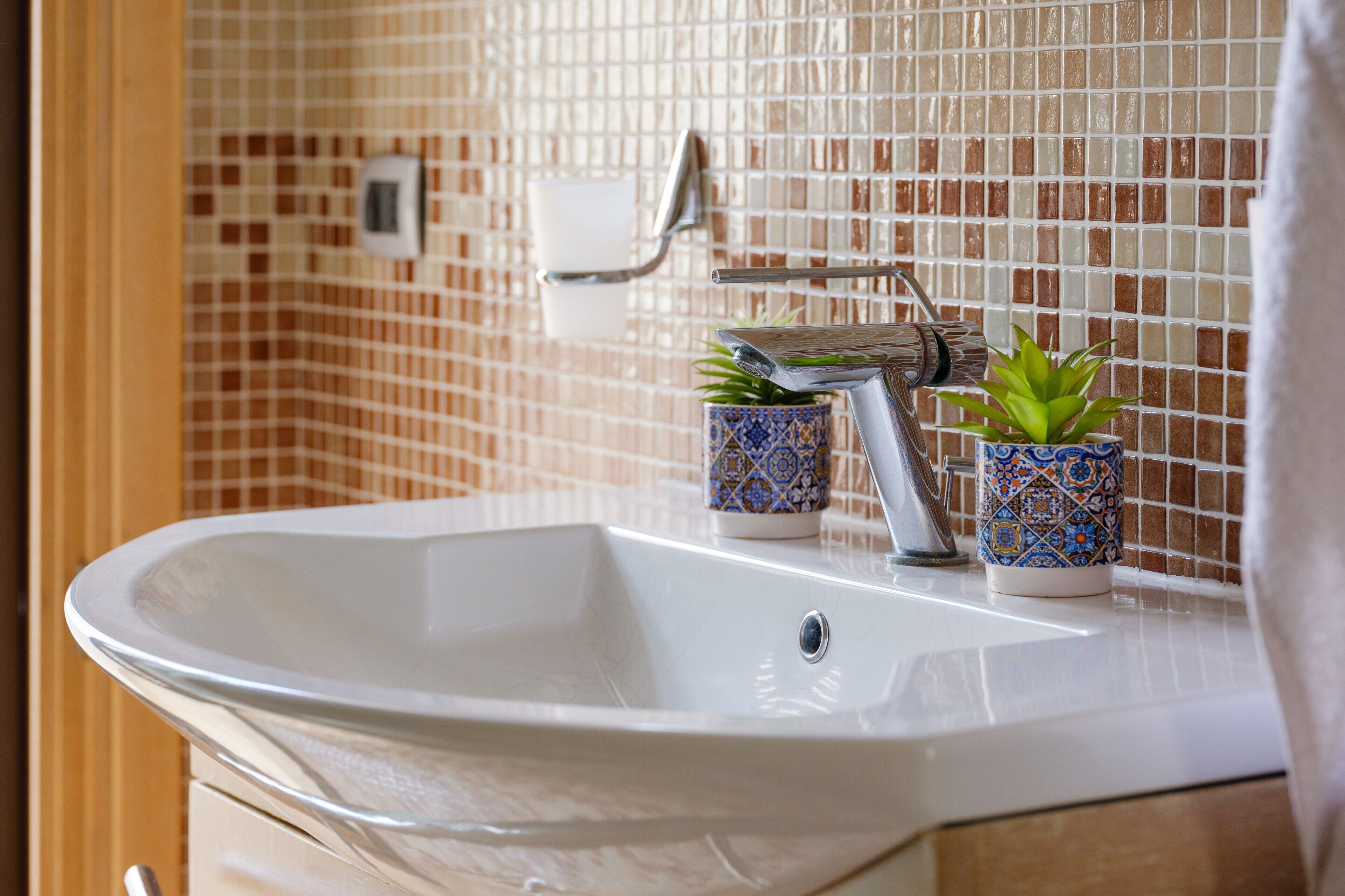 Une salle de bain avec un lavabo blanc, un porte-serviettes et deux plantes en pot.
