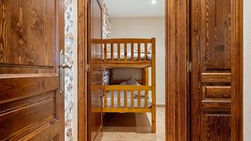 Una cama litera de madera en una habitación con un muro de piedra decorativo y puertas de madera.