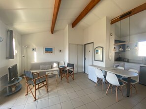 A modern living room with a sofa, chairs, a TV, and a dining area with a table and chairs.
